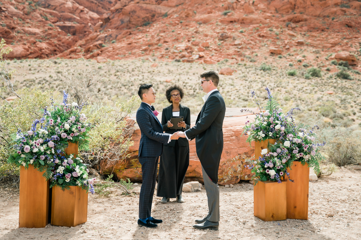 Newlyweds taking their vows at an outdoor wedding ceremony in a Las Vegas desert.