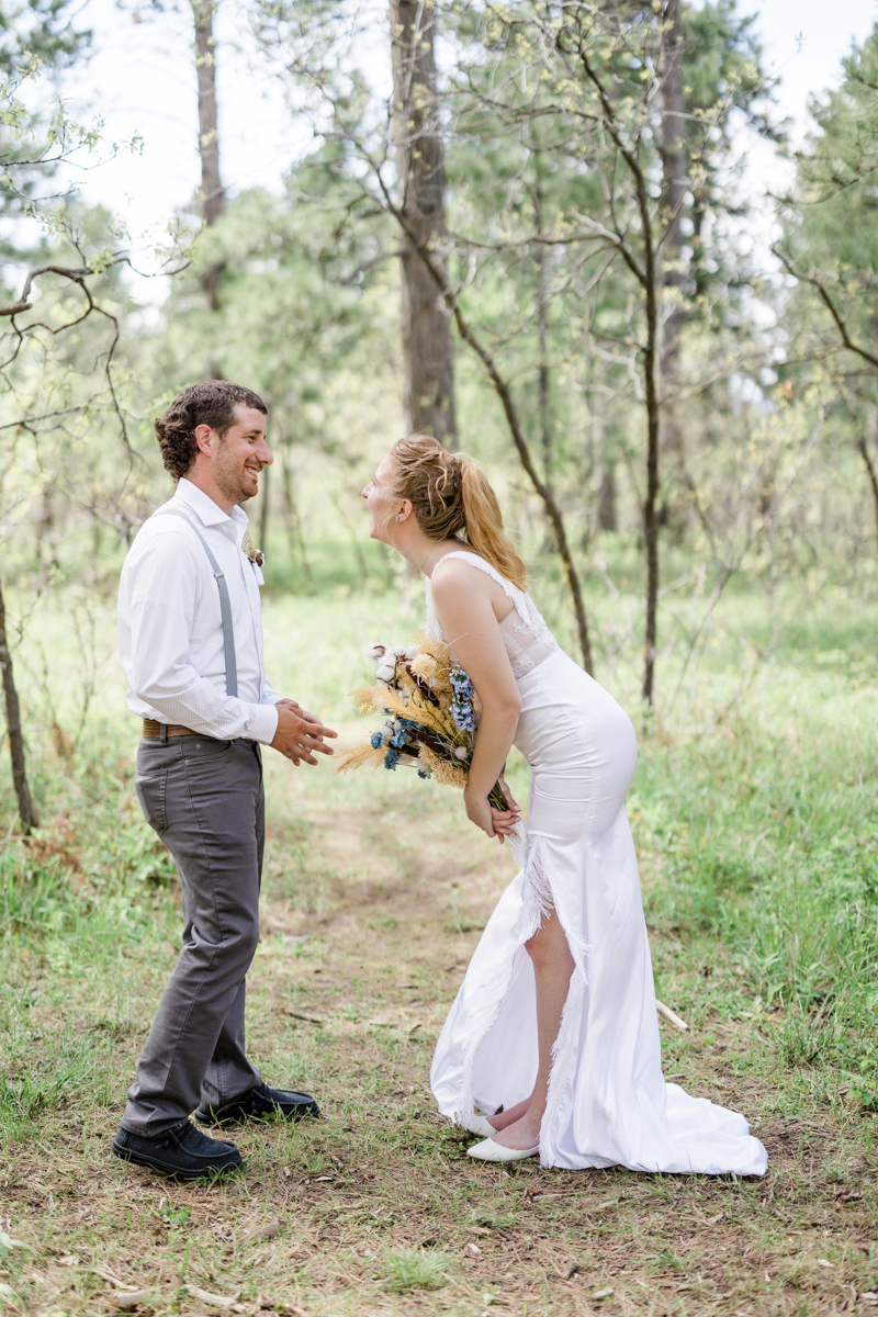 Bride and groom sharing a laugh during their wedding ceremony outdoors.