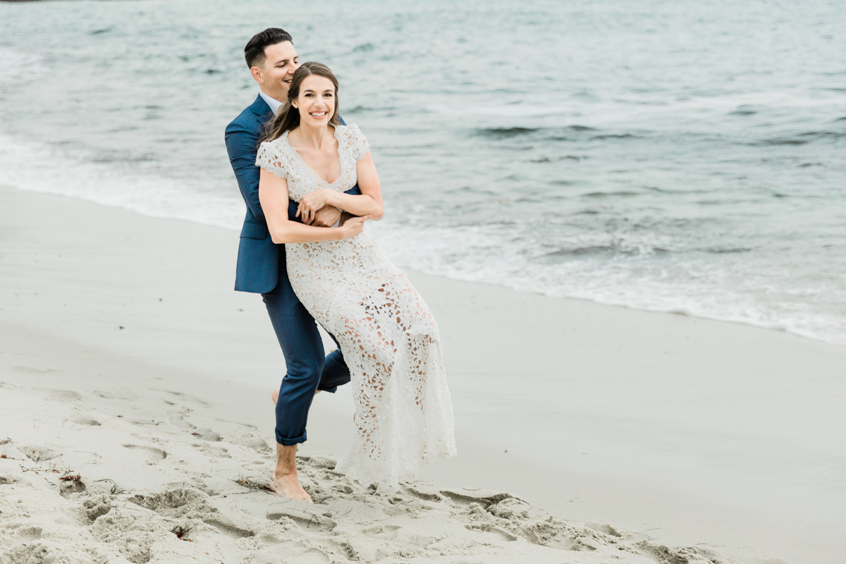 Groom lifting bride during their private wedding on the beach in San Diego.