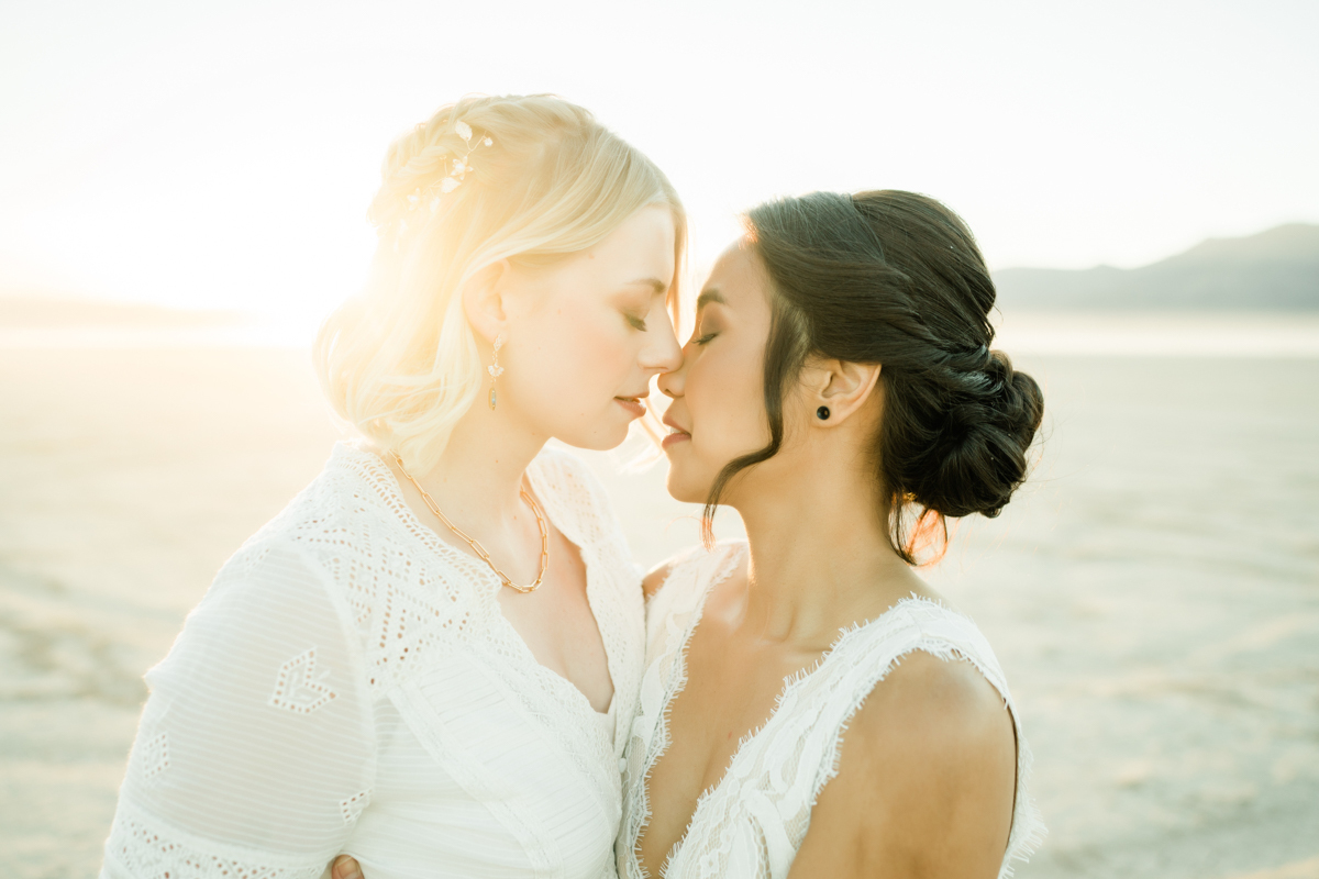 Two brides in an embrace about to kiss for a sexy wedding photo.