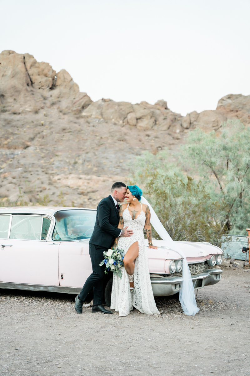 Bride and groom leaning against an old car taking a sexy wedding photo.