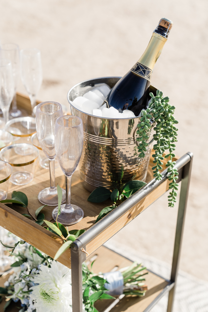 Bucket filled with ice and uncorked bottle of champagne, surrounded by glass champagne flutes.
