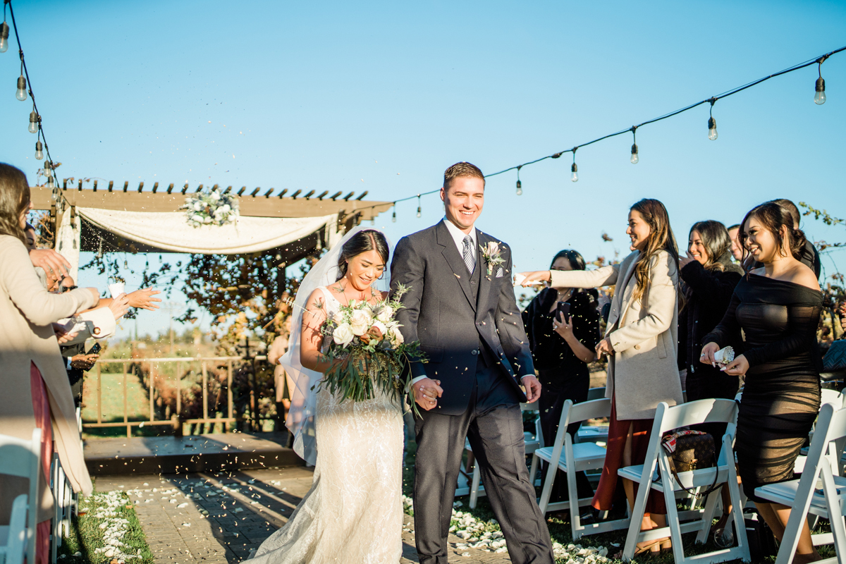 Bride and groom holiday hands as they walk past their guests at their wedding ceremony.