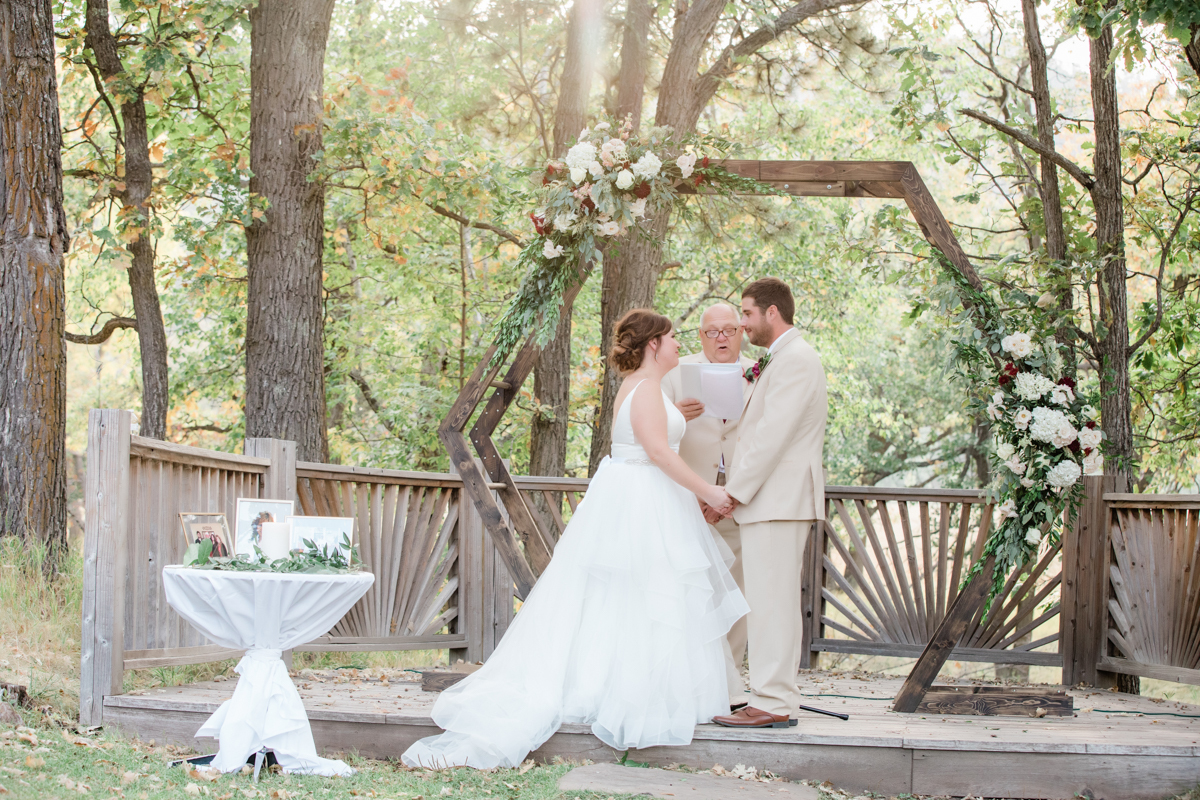 Bride and groom holding hands while an officiant reads vows to them.