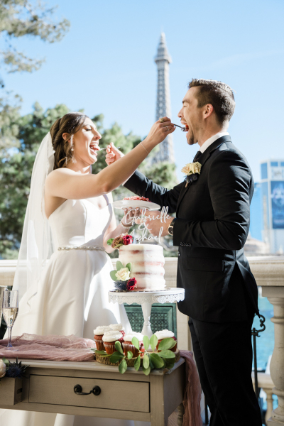 A bride and groom use forks to serve each other a bite of cake at wedding ceremony celebration at the Bellagio in Las Vegas.