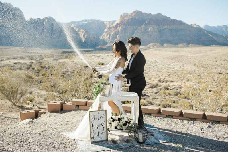 Champagne sprays from a bottle as a couple celebrates their outdoor wedding at Red Rock Canyon in the Southern Nevada desert.