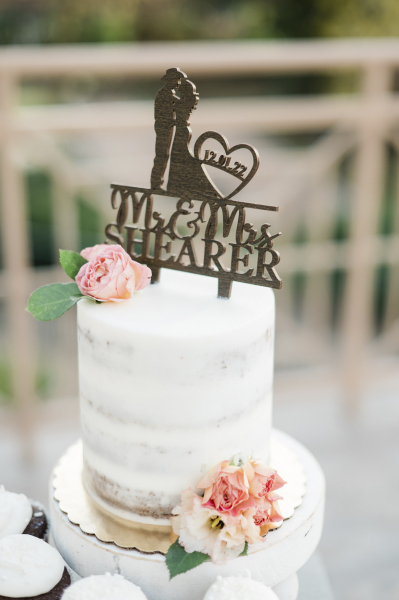 Wooden die cut cake topper with a cowboy and his bride and the names "Mr. & Mrs. Shearer" presented on a wedding cake.