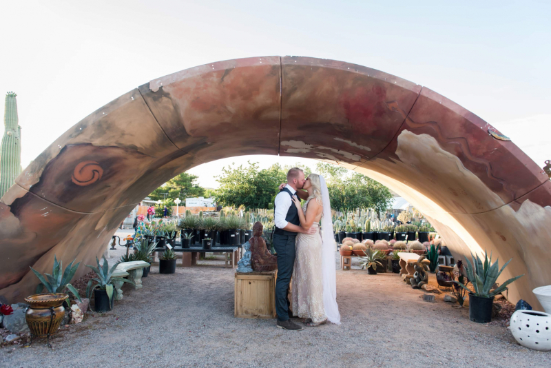 A couple kisses underneath a large metal tunnel at the Cactus Joe’s Blue Diamond Nursery.