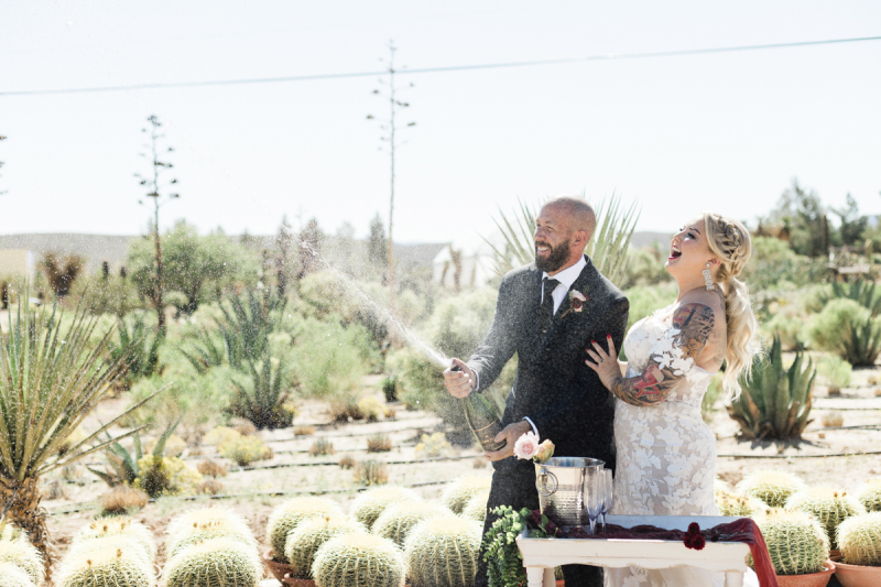 A couple sprays Champagne to celebrate their wedding amongst a collection of barrel cacti and agave. A couple sprays Champagne to celebrate their wedding amongst a collection of barrel cacti and agave.