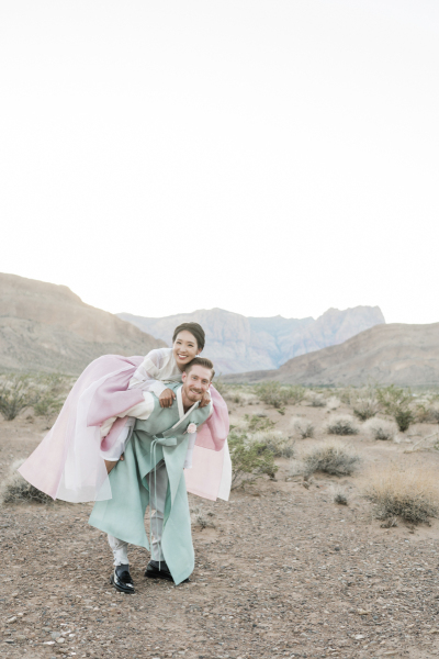 A bride jumps on the back of her groom as they pose for wedding photos in the Mojave Desert. A bride jumps on the back of her groom as they pose for wedding photos in the Mojave Desert.