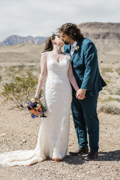 A bride and groom hold hands and kiss on their wedding day in the Mojave Desert. A bride and groom hold hands and kiss on their wedding day in the Mojave Desert.