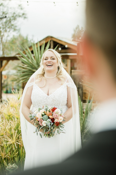 A bride laughs while looking at her groom who is out of focus in the foreground. A bride laughs while looking at her groom who is out of focus in the foreground.