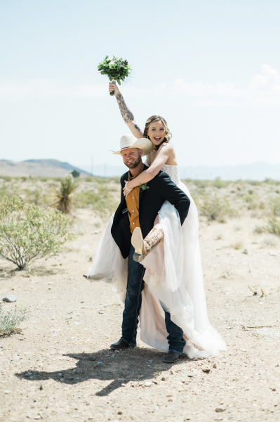 A groom carries his bride piggyback-style as the couple celebrates their wedding in the Mojave Desert. A groom carries his bride piggyback-style as the couple celebrates their wedding in the Mojave Desert.