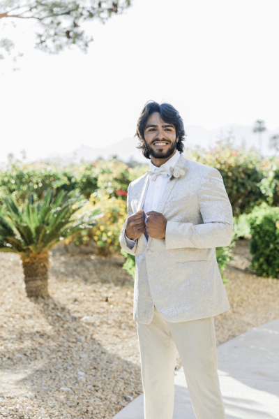 Groom holding tuxedo smiling.