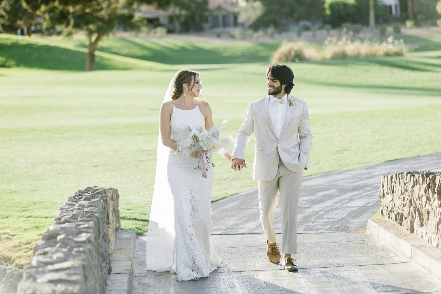 Wedding couple walking hand in hand along a path at Canyon Gate Country Club.