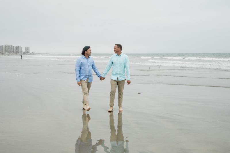 Couple walking hand in hand along the beach.