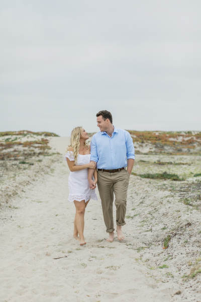 Couple walking hand in hand in sand.