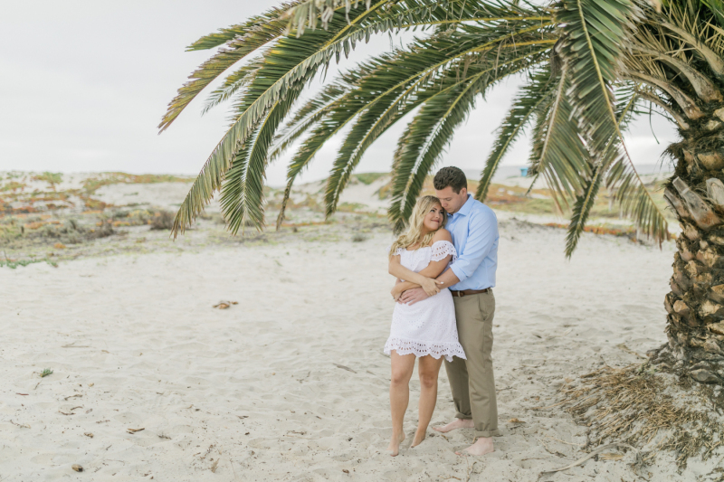 Couple embracing under a palm tree.