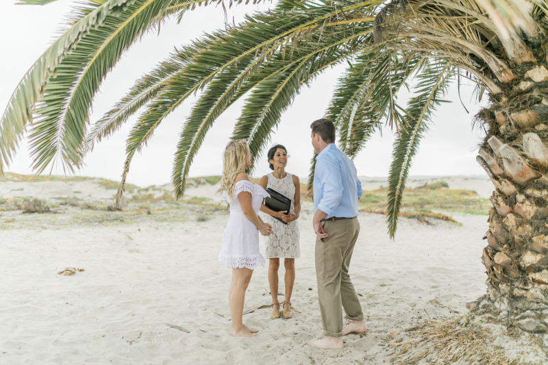 Couple at ceremony under a palm tree.