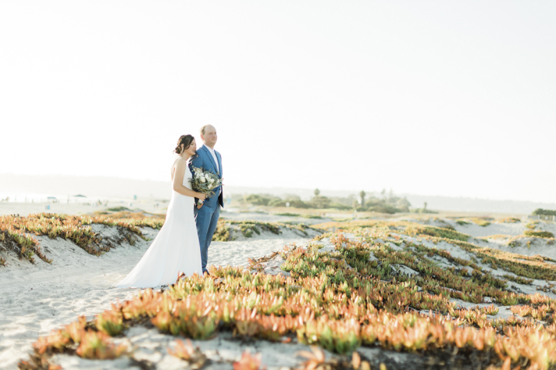 Couple standing in beach sand.
