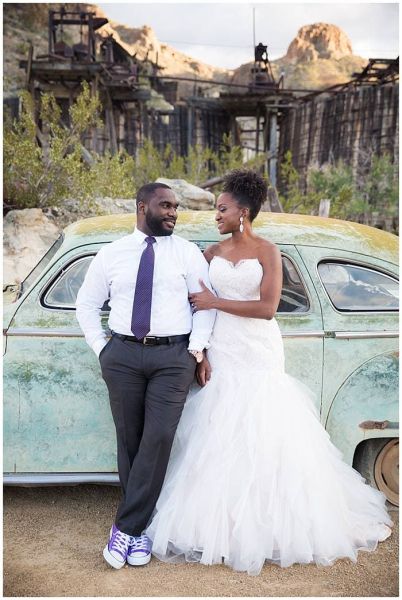 A groom and bride pose for wedding photos as they lean against the side of a vintage car in Eldorado Canyon.