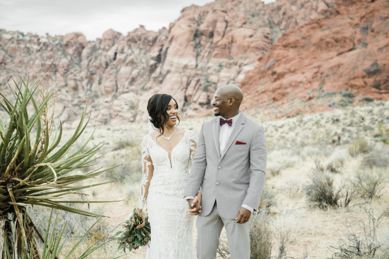 Bride and groom walking and talking with desert background.