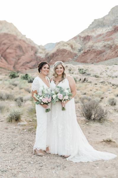 Same sex wedding couple standing side by side with wedding bouquets.