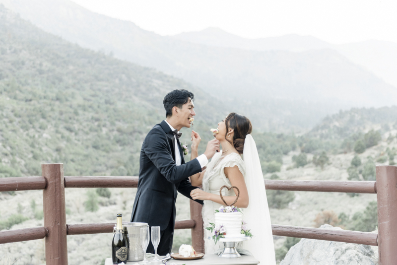 Bride and groom feeding each other a piece of cake.