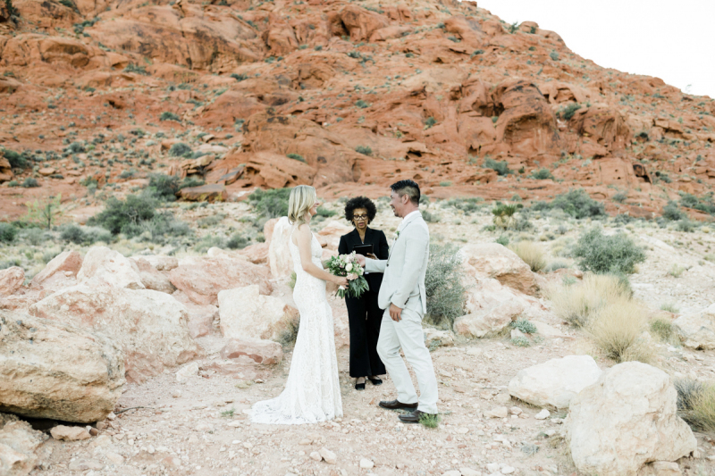 Bride and groom in front of officiant with desert backgound.
