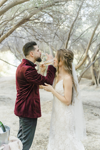 Newlywed couple crossing arms while drinking champagne.