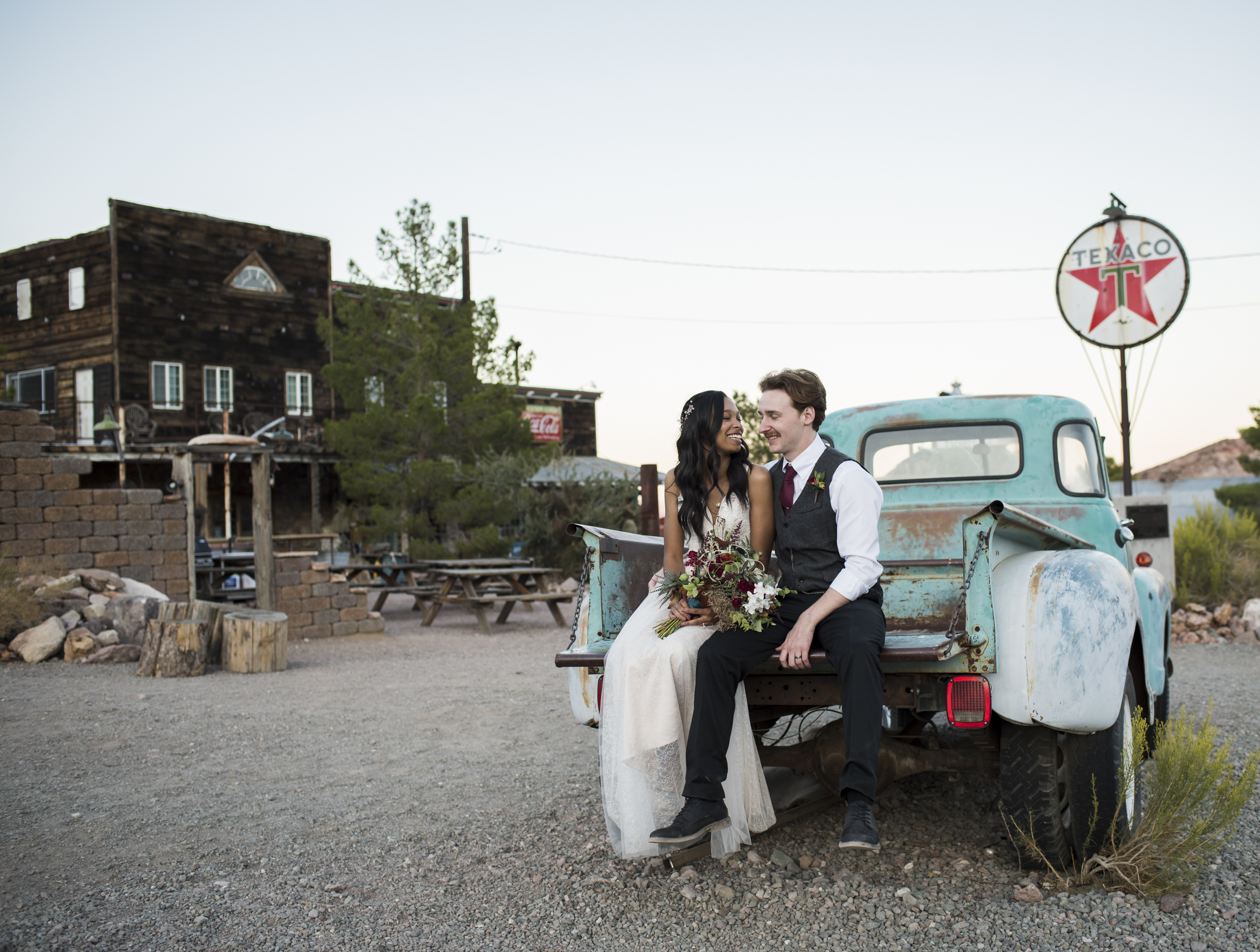 Newlywed couple sitting in the bed of a truck.