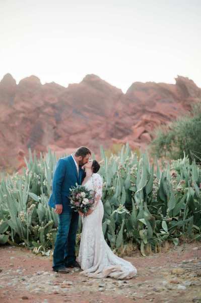 Newlywed couple kissing in front of cacti at Valley of Fire.