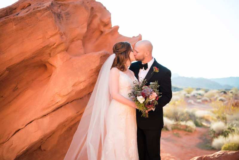 Bride and groom kissing while bride holds her bouquet.