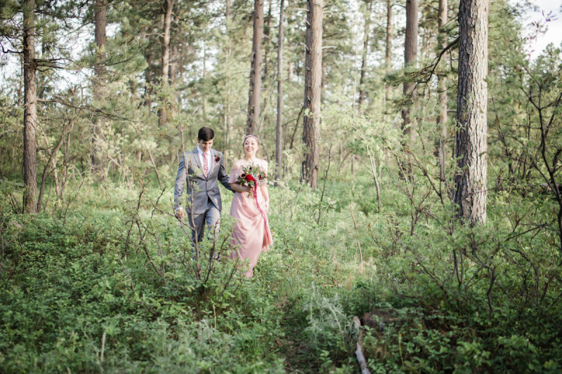 A groom and bride walk through a thicket of underbrush in a forest on their wedding day in the Black Hills of South Dakota.