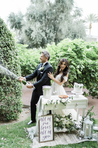 Groom popping open champagne for their ceremony celebration.