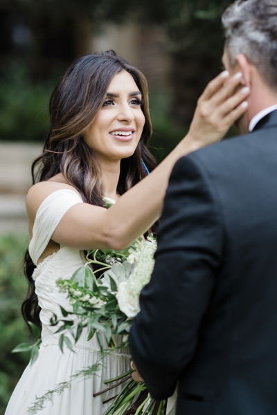 Bride brushing away groom\'s tears during ceremony.