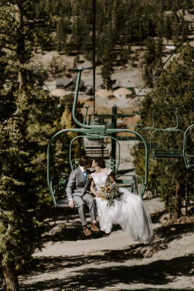 A bride and groom kiss while riding a ski lift at Lee Canyon ski resort near Las Vegas on their summer wedding day.
