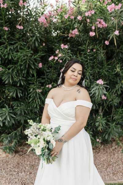 A medium shot of a bride posing for a portrait in front of a hedge at Lotus House in Las Vegas.