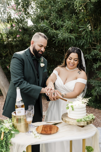 A groom and bride cut their wedding cake in a garden at Lotus House.