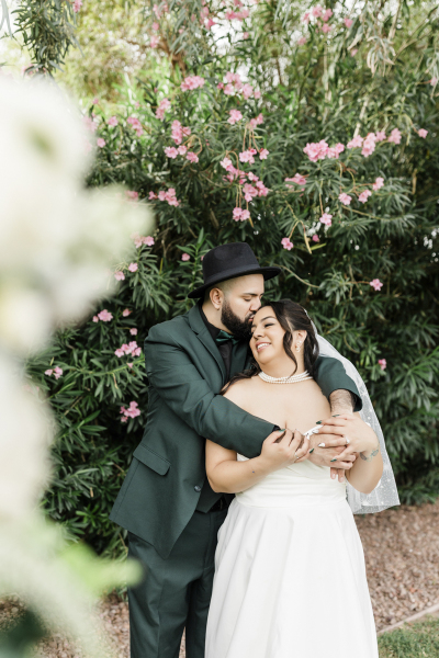 A bride and groom embrace as they pose for wedding photos in the garden at the Lotus House in Las Vegas.