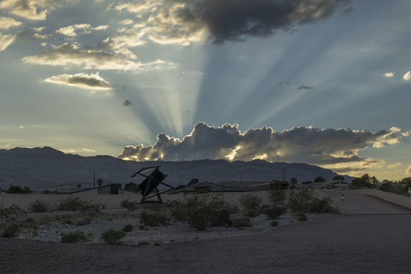 Rays of sunshine poke through the clouds as the setting sun falls behind the mountains west of Las Vegas at the Rita Deanin Abbey Art Museum.