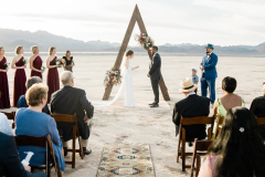 A bride reads her vows to her groom as guests and bridal party looks on in Dry Lake Bed near Las Vegas.