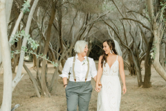 Two brides look at each other and laugh among bare trees at GreenGale Farms.