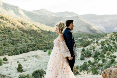 A bride in a celestial dress stands back to back with her groom in Mt. Charleston.