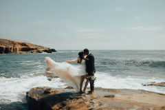 A bride and groom standing in front of the ocean in Point Loma.