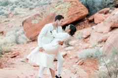 A groom dips his bride among red rocks at Red Rock Canyon.