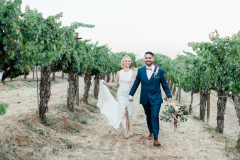 A bride and groom walk toward the camera smiling at Wilson Creek Winery.