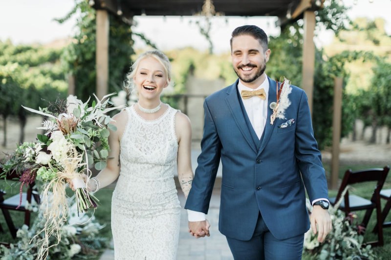 Bride smiling walking hand in hand with groom.