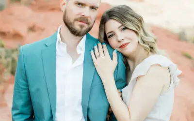 Woman resting head on man's shoulders displaying engagement ring.