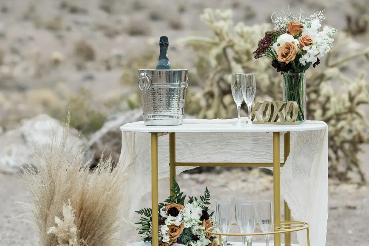 Champagne and flowers on table in desert for a ceremony celebration.